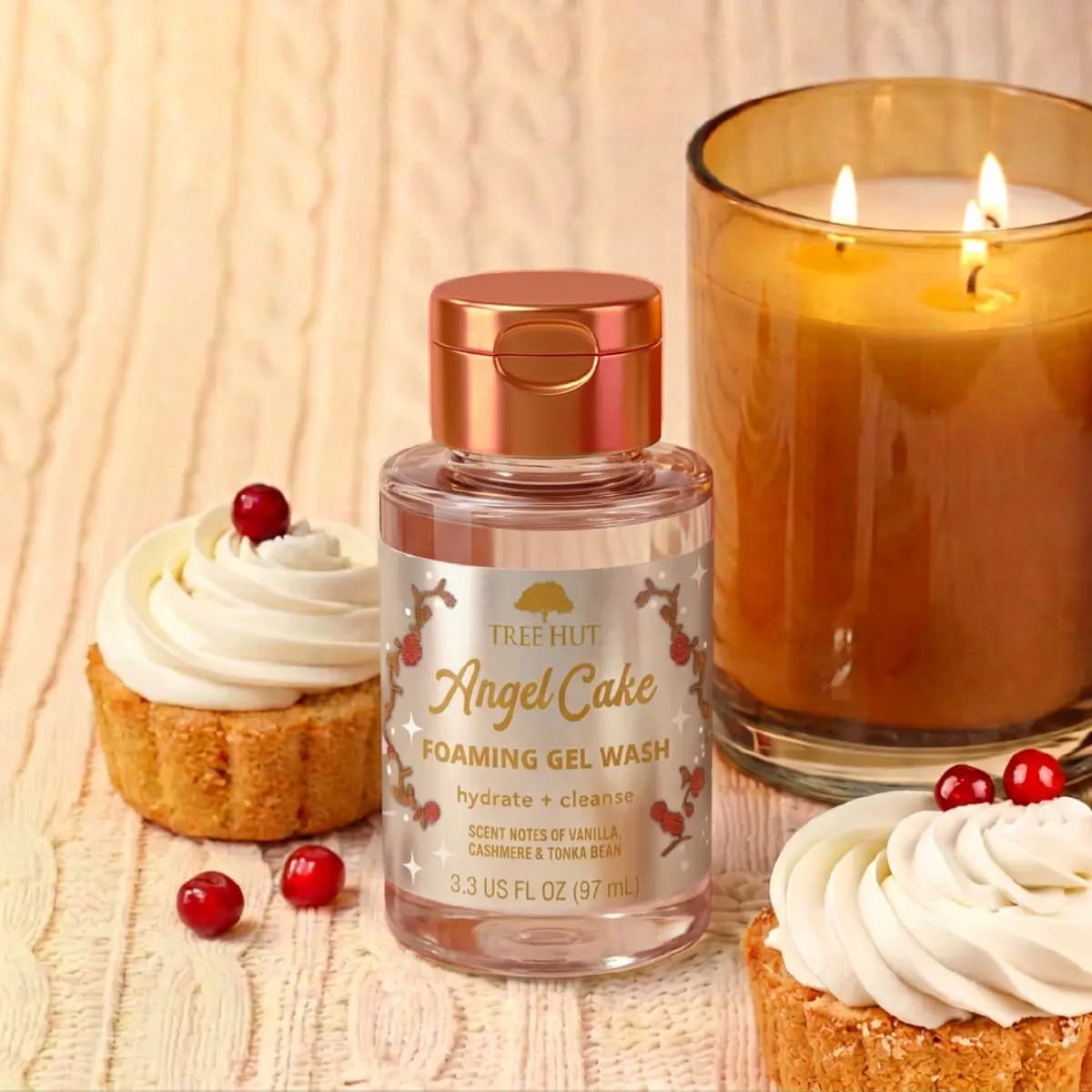 Mini Foaming Gel Wash between frosted cupcakes, red berries and a glowing amber candle on knit fabric