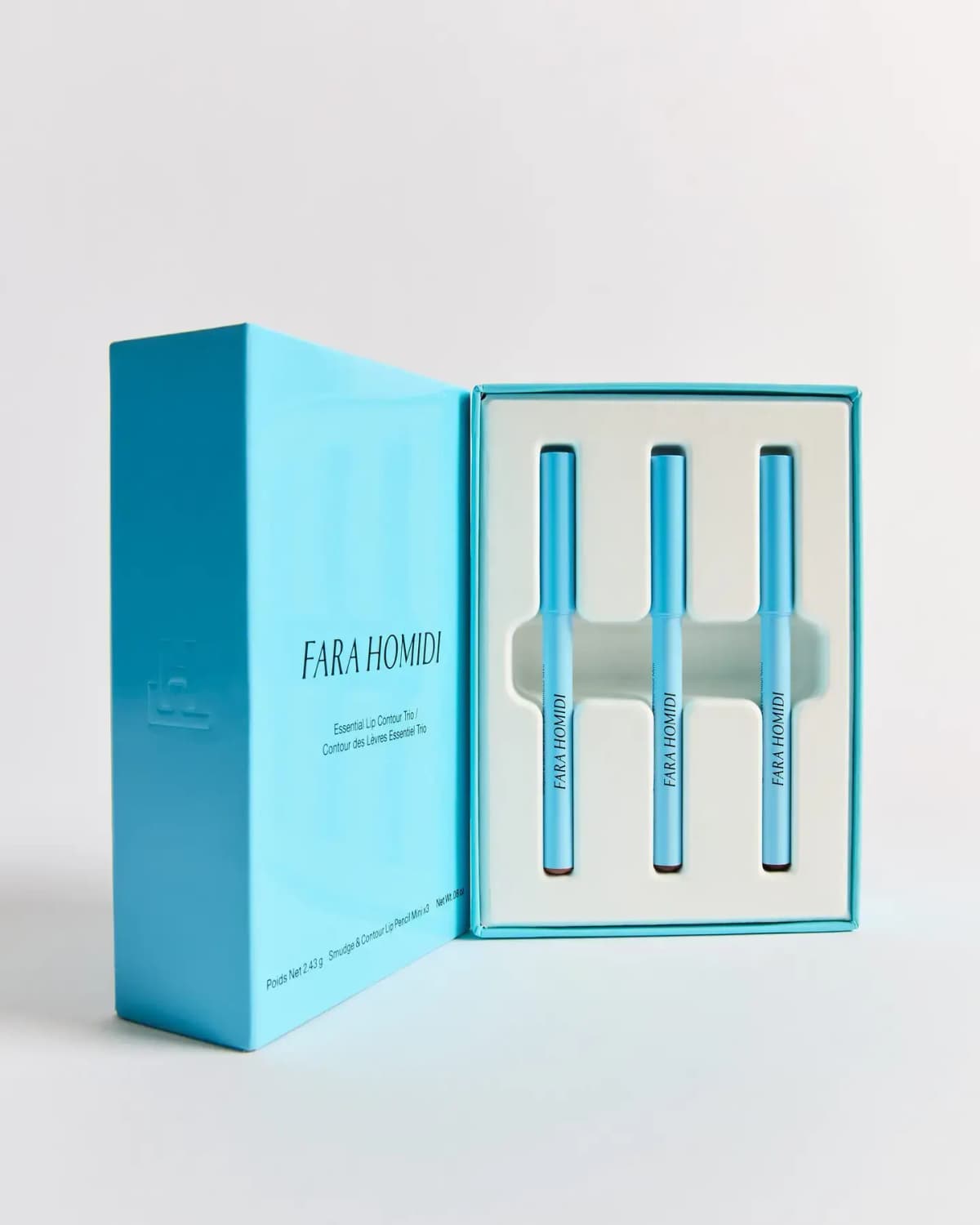 Open sky-blue Fara Homidi Essential Lip Contour Trio box holding three mini blue lip pencils in a white insert
