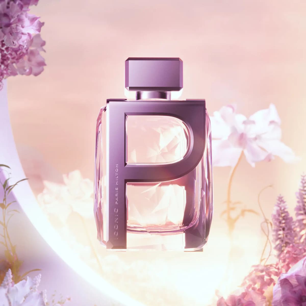 ICONIC Paris Hilton bottle with mauve metallic P frame and faceted pink glass, floating among soft pink and lilac flowers
