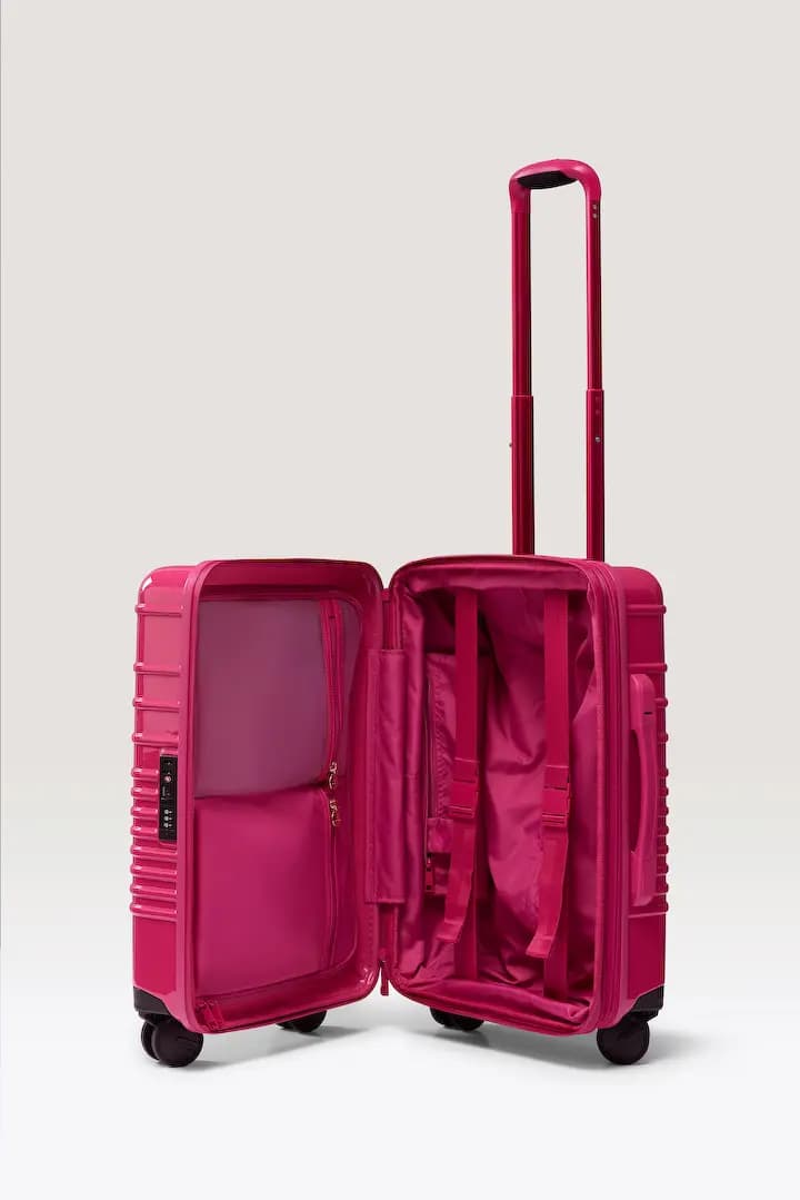 Open carry-on showing pink lining, zippered mesh compartments and compression straps