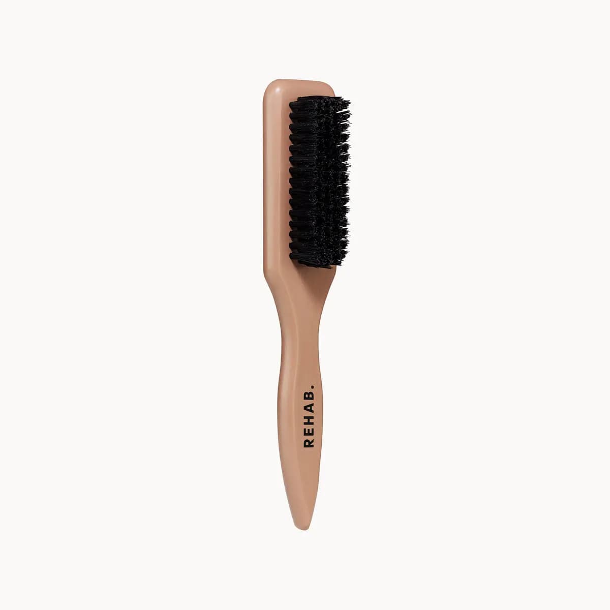 Nude-handled teasing brush with dense black bristles and Rehab logo printed on the handle