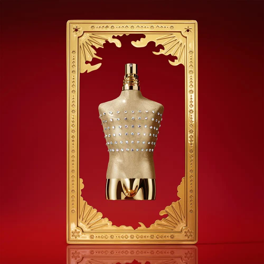 Gold mesh torso bottle with crystal studs and chrome base framed by a gilded tarot card on red