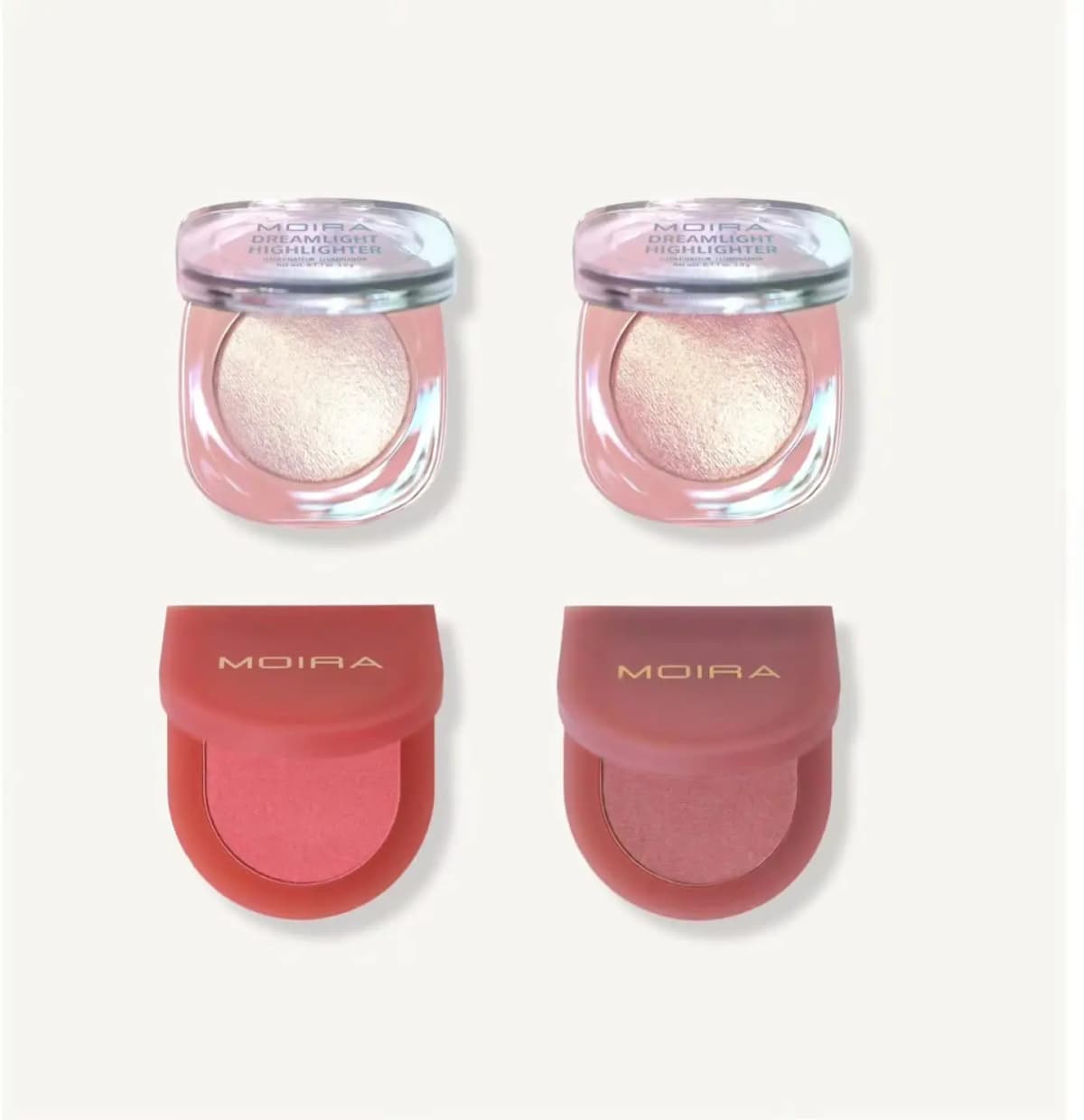 Two Moira Dreamlight Highlighter compacts with clear lids above two Moira blush compacts in red and mauve casings.