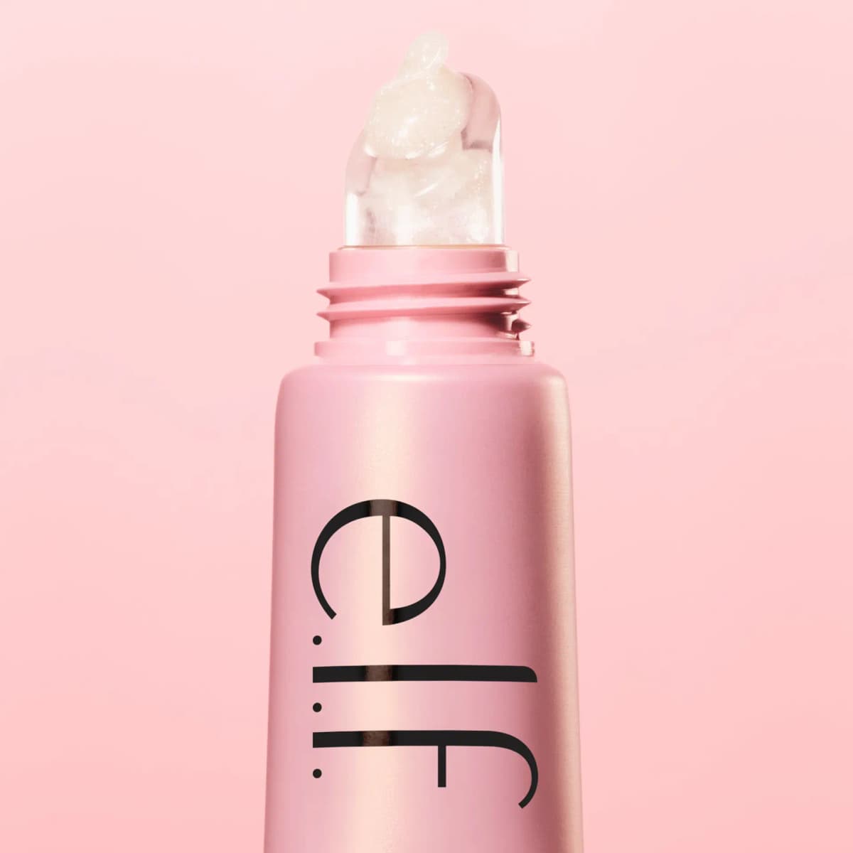 Uncapped pink e.l.f. tube with a swirl of clear, shimmering balm on the silicone tip against a soft pink background