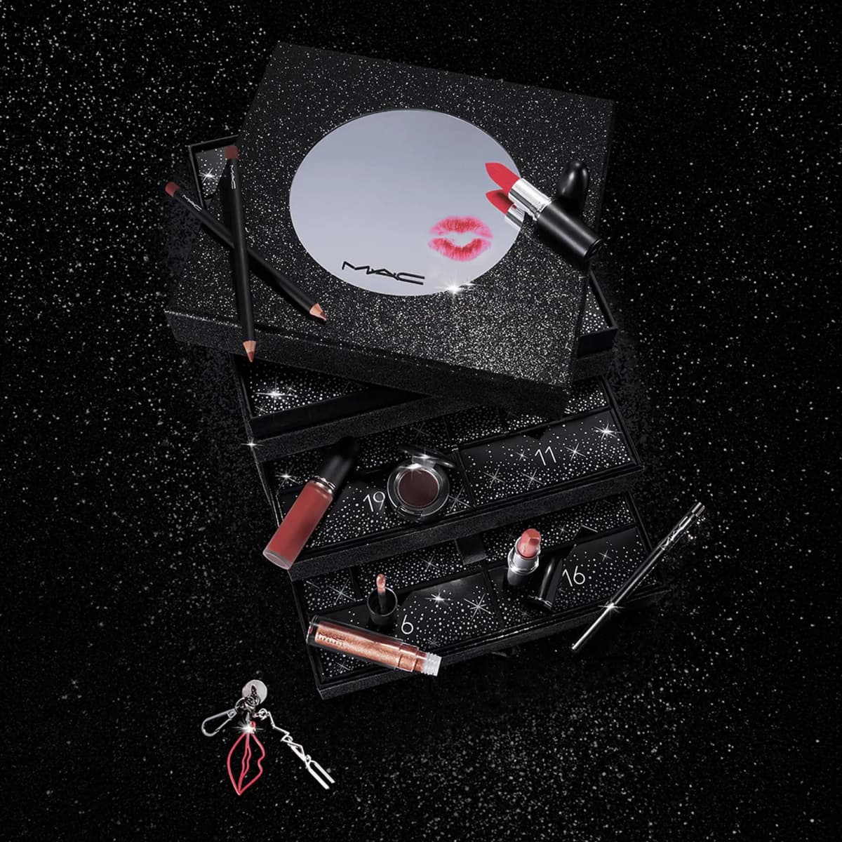 Overhead of mirror lid with red lipstick and kiss print, lip pencils, liquid lipstick and lips-shaped charm