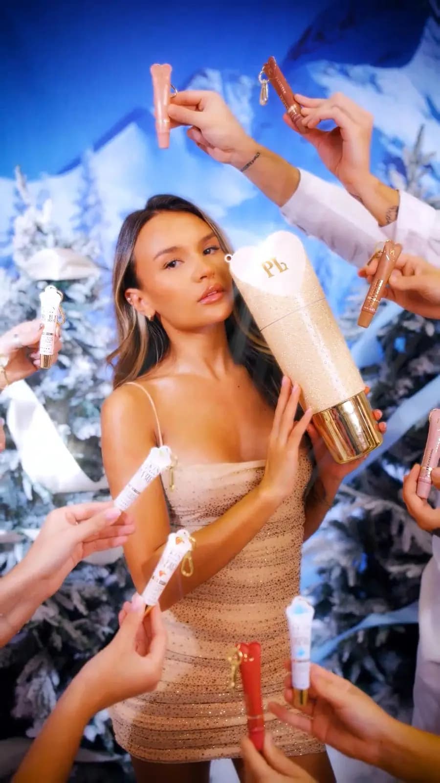 P.Louise XL Protect Your Pout Christmas set in a giant glitter gold tube, held by a model amid hands holding lip tubes