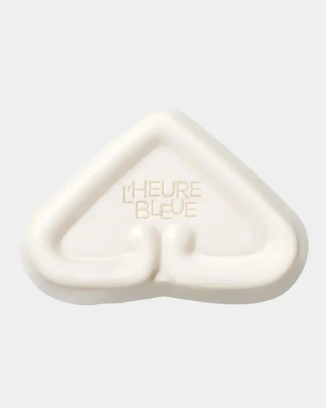 White heart-shaped soap bar embossed with L'Heure Bleue, its raised border echoing the bottle stopper.