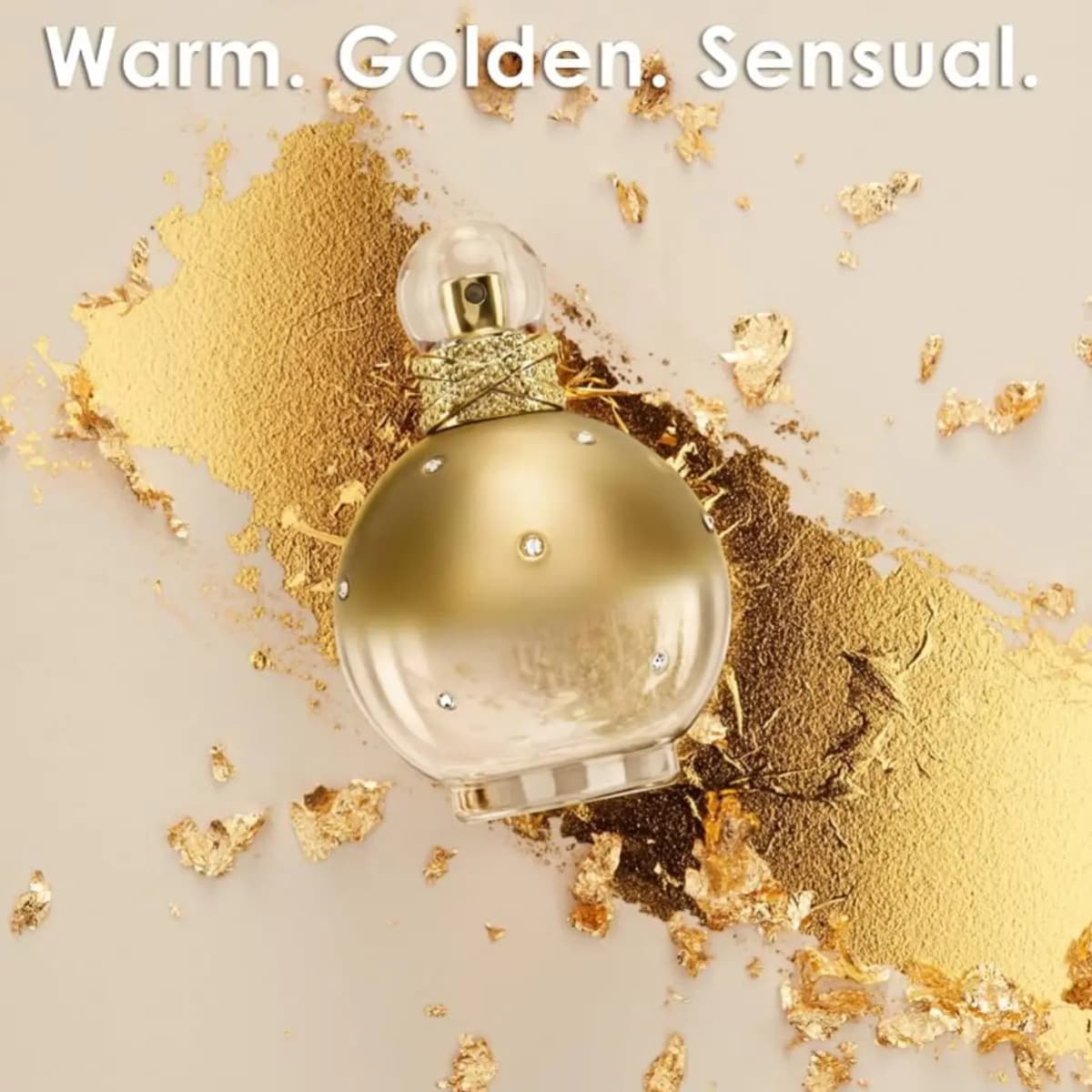Gold-hued Goddess Fantasy bottle laid on a streak of shimmering gold powder beneath the words Warm. Golden. Sensual.