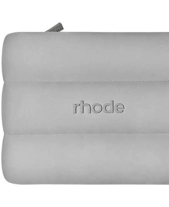 Close-up of grey puffy quilted Rhode zip pouch showing embossed rhode logo and top zipper detail