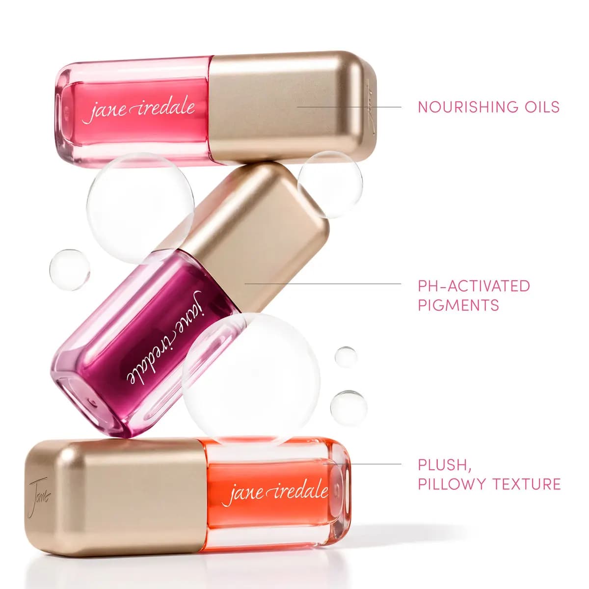 Stacked pink, berry and coral jane iredale lip oils labelled with nourishing oils, pH-activated pigments and plush texture.