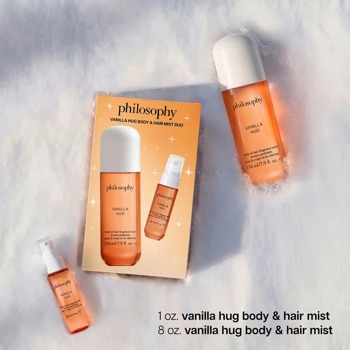 Orange philosophy vanilla hug body and hair mist duo box with large white-capped mist and small spray bottle on snow