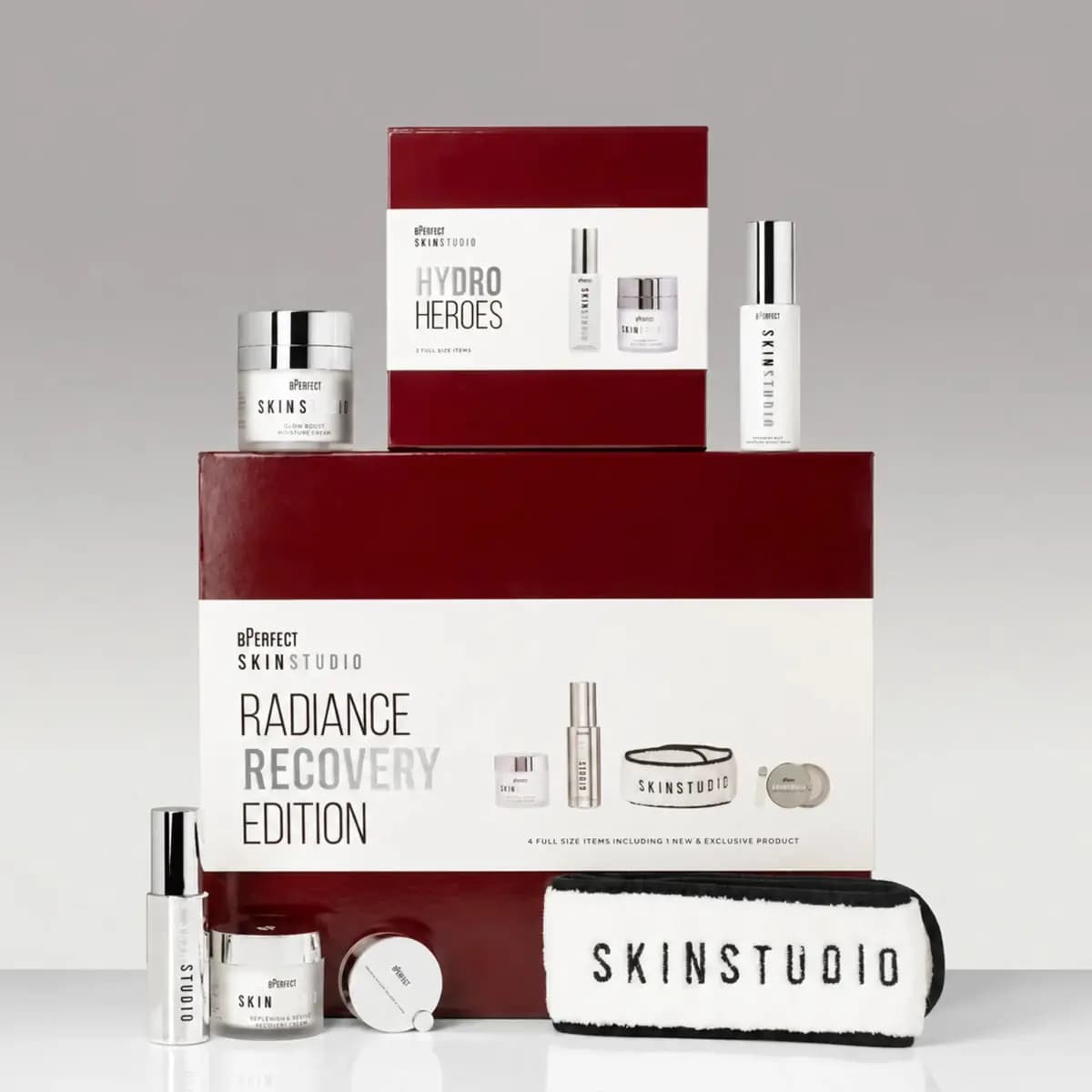 BPerfect Skin Studio Radiance Recovery Edition and Hydro Heroes boxes stacked with silver-capped skincare and headband