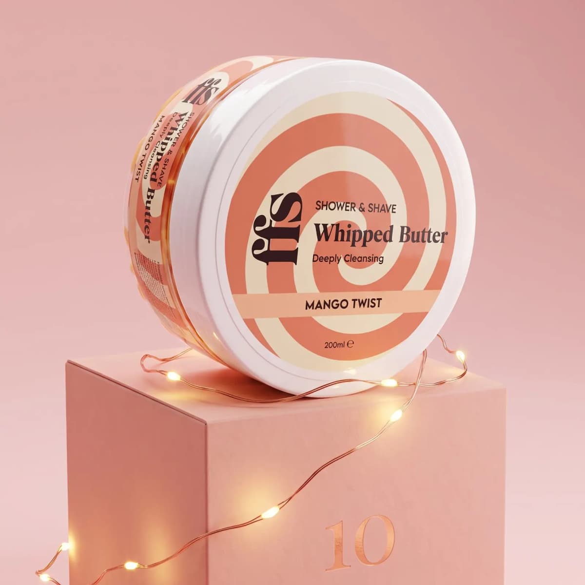 FFS Whipped Butter Mango Twist tub with orange swirl lid on pink box number 10 wrapped in fairy lights