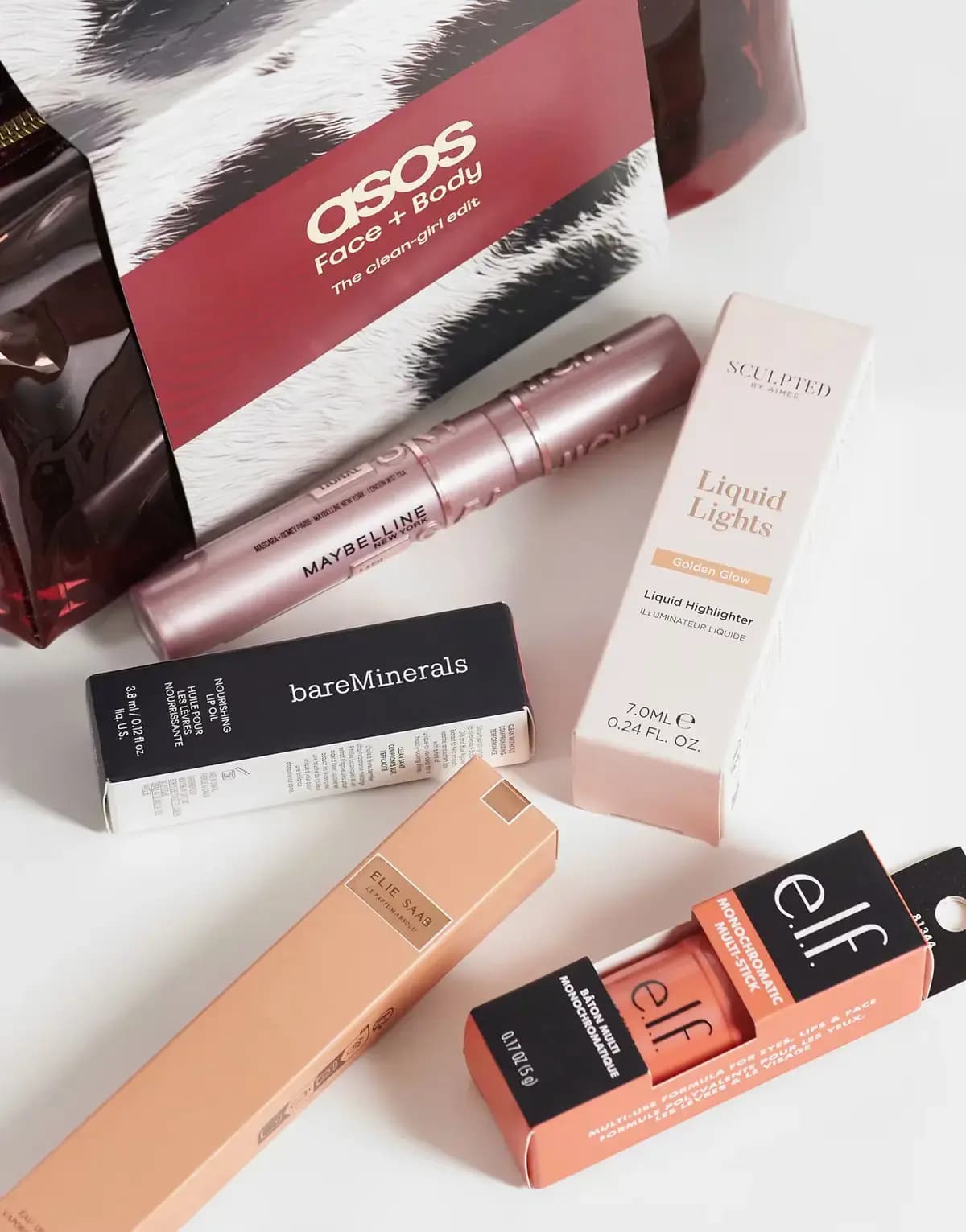 Pink Maybelline mascara with boxed Sculpted Liquid Lights, bareMinerals lip oil, Elie Saab perfume and e.l.f. multi-stick