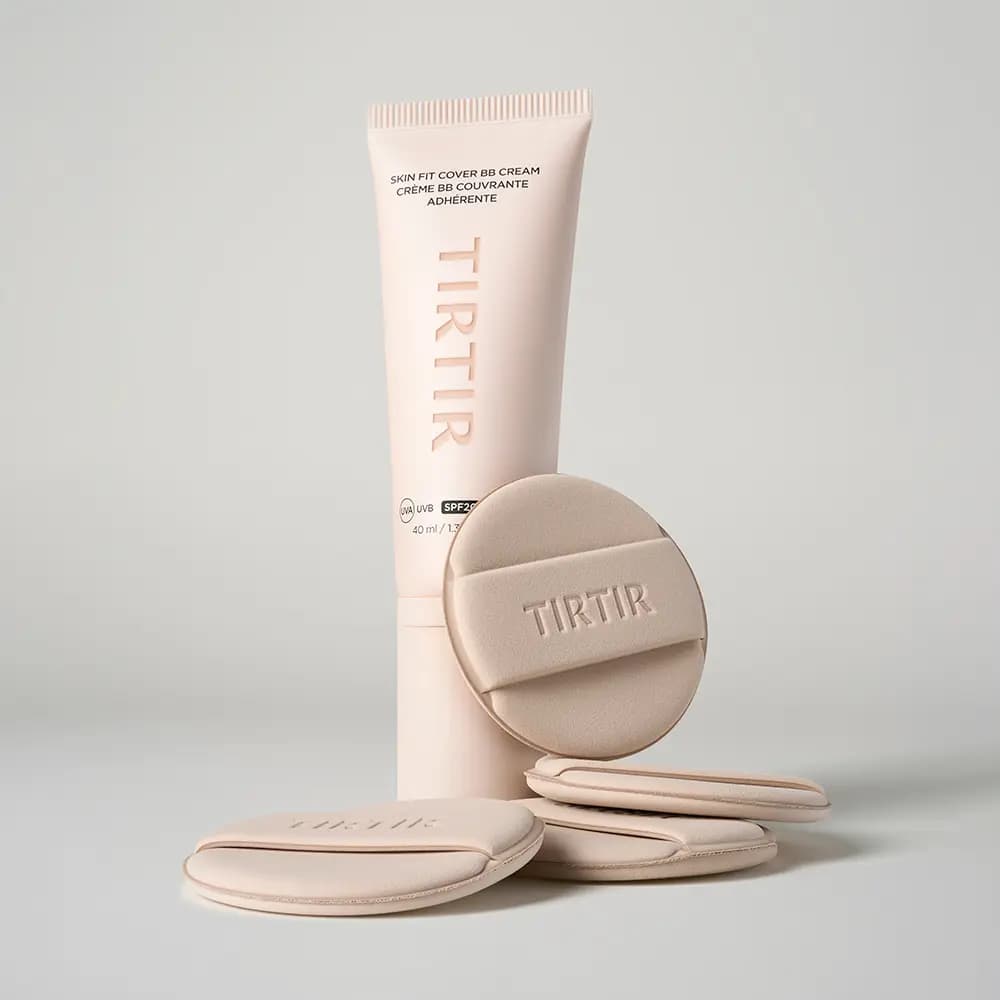 Upright pale pink BB cream tube with four beige TIRTIR-embossed makeup puffs propped and stacked around its base