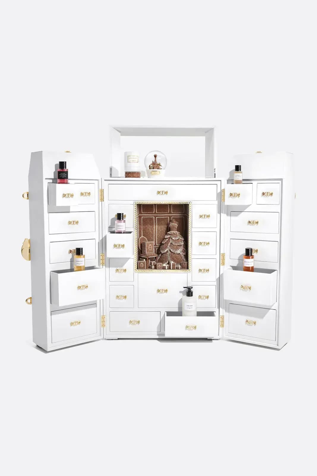 White advent calendar trunk with 24 candy-handle drawers displaying perfumes, candle, snow globe