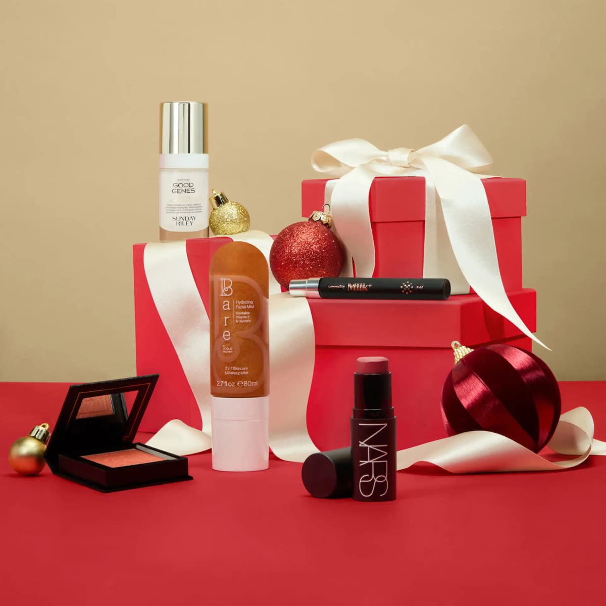Sunday Riley Good Genes, Bare facial mist, NARS stick and Milk+ pen staged with red gift boxes and satin ribbon