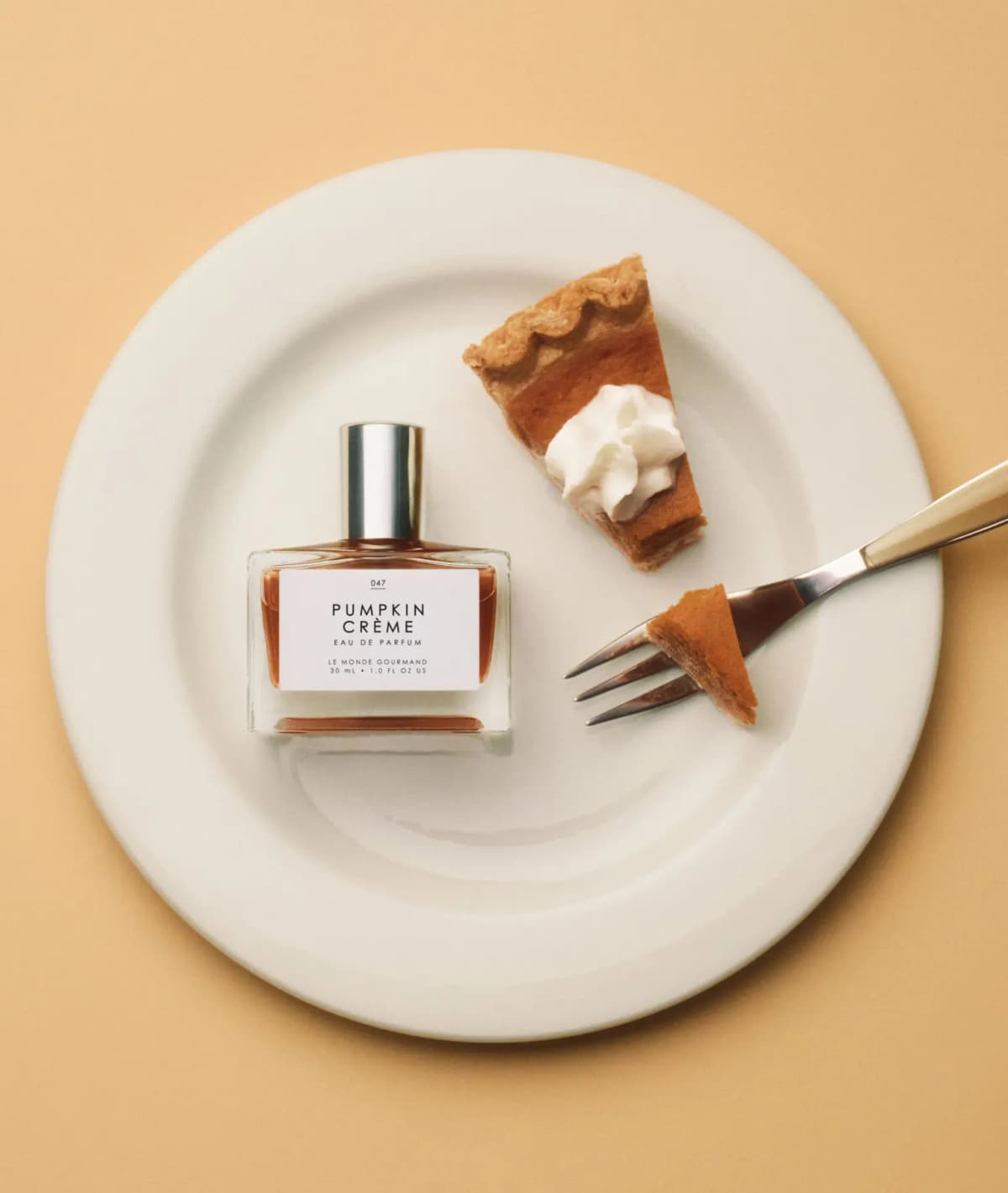 Overhead view of Pumpkin Crème bottle on a white plate with a pumpkin pie slice, whipped cream and a fork