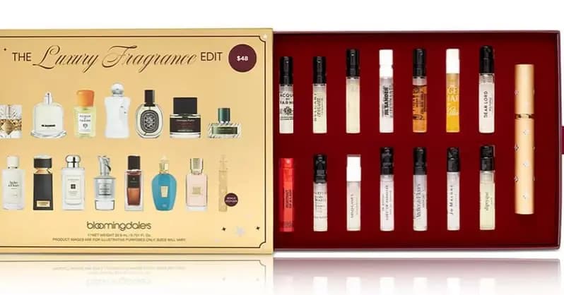 Open gold gift box labeled The Luxury Fragrance Edit $48 Bloomingdale's, revealing 14 slim fragrance sample vials.