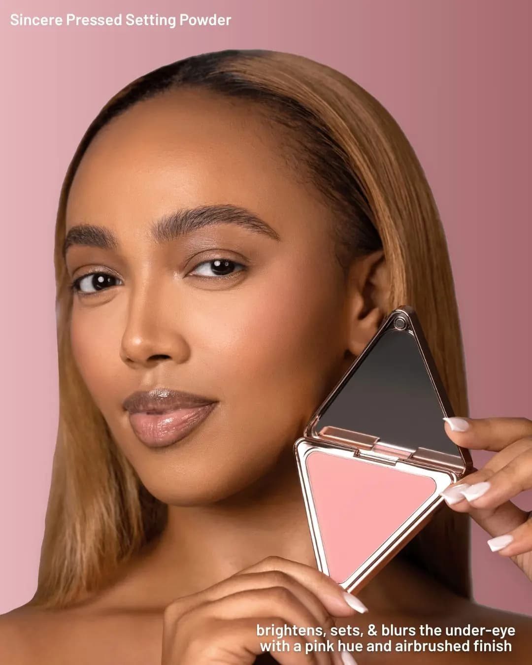 Model with straight blonde hair holds an open triangular rose-gold Sincere pressed powder compact with a pink pan and mirror