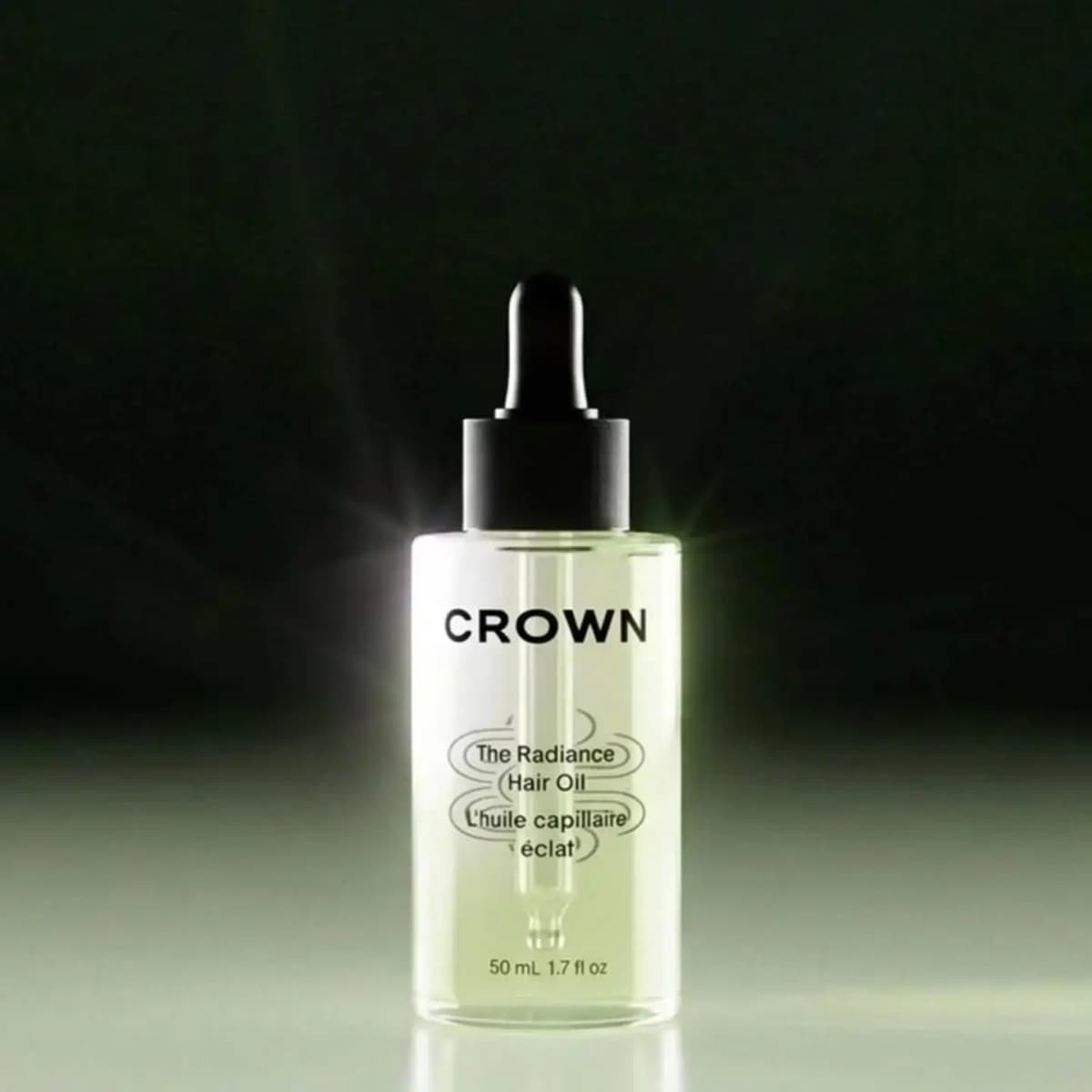 Clear glass Crown The Radiance Hair Oil dropper bottle, 50 mL, with pale green oil and black dropper cap