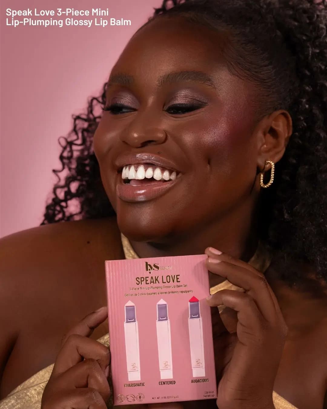 Smiling model with glossy nude lips holds the Speak Love 3-piece mini lip balm set box with Charismatic, Centered