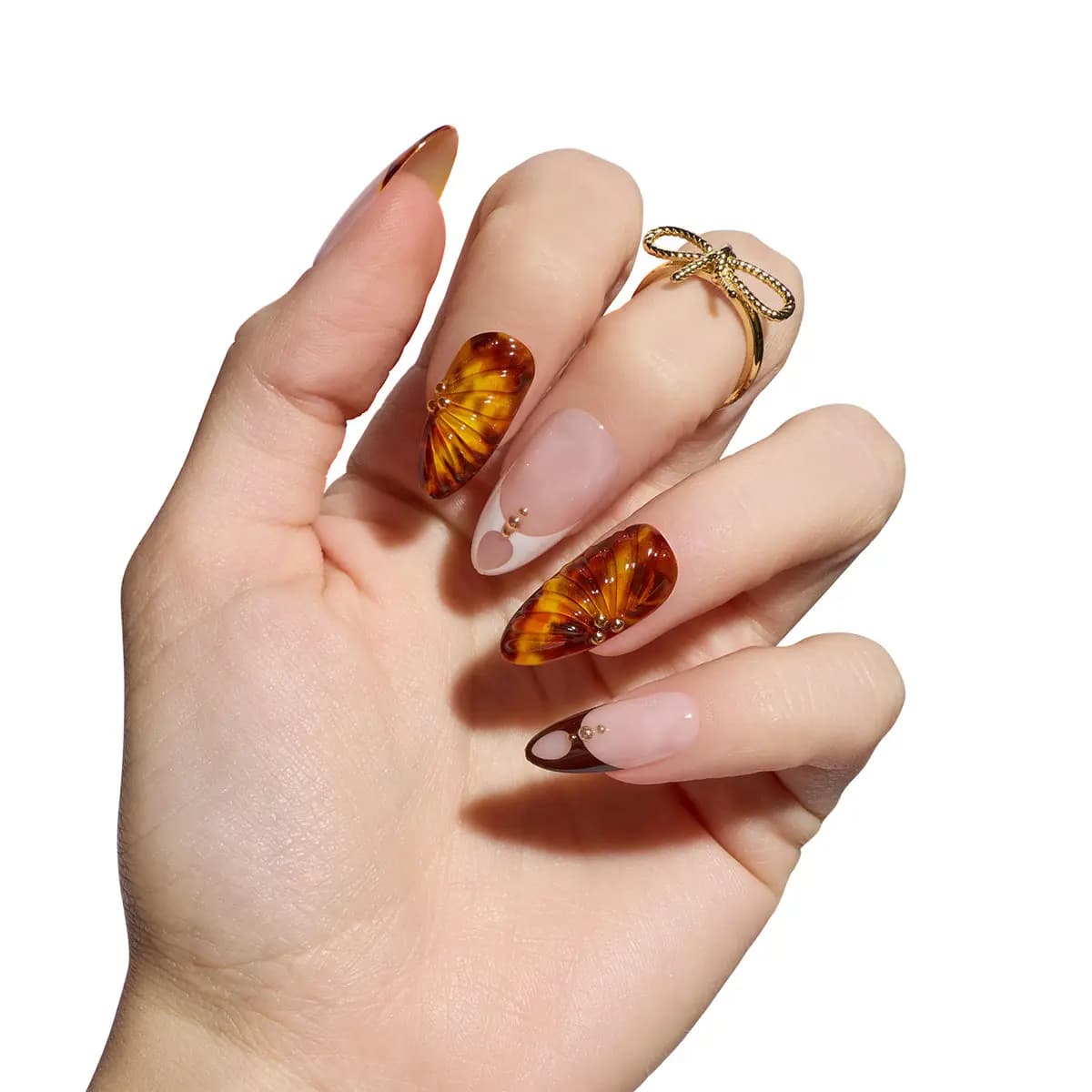 Hand wearing Abstract Tortoise nails: ridged amber tortoiseshell with gold beads beside white and brown heart French tips.