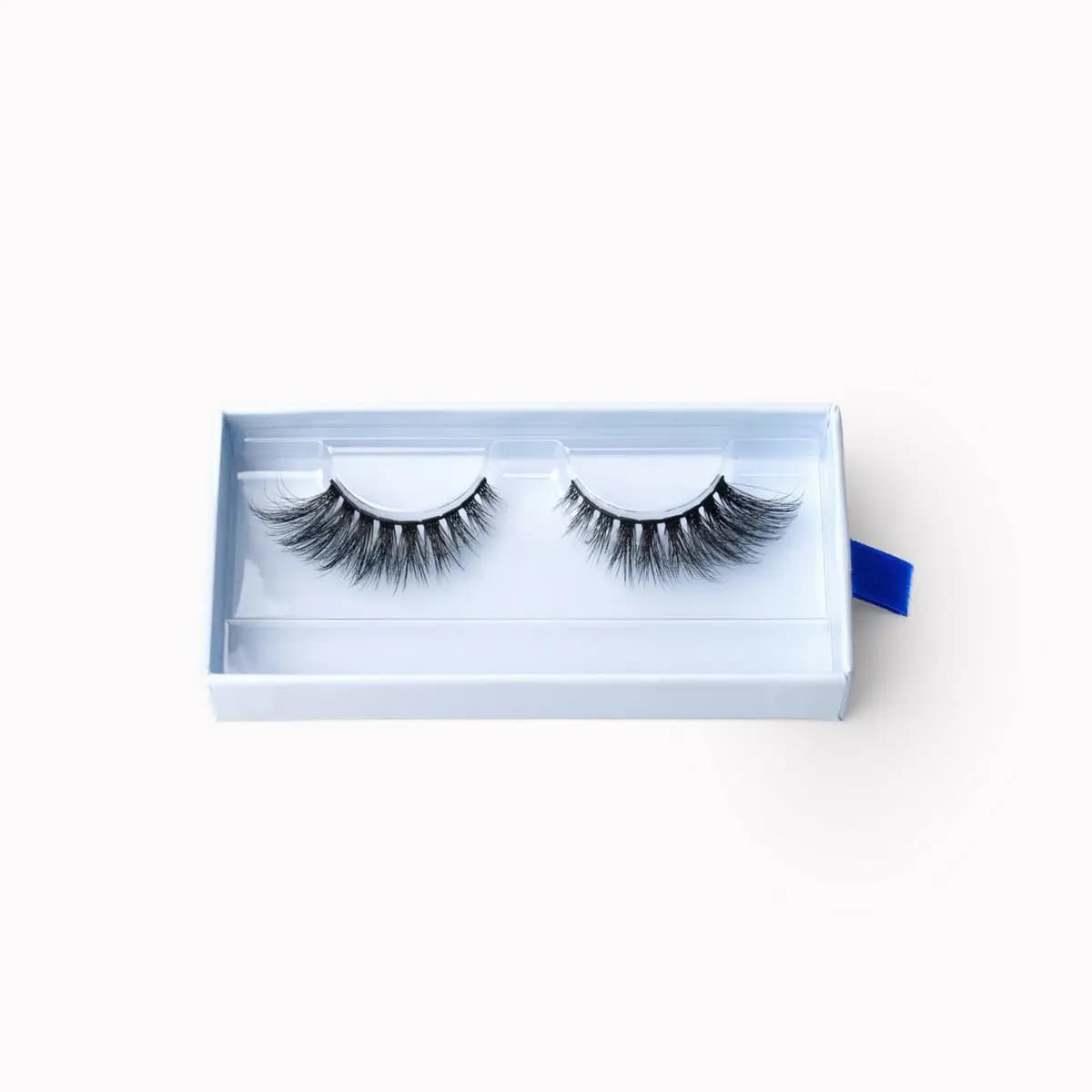 Overhead view of a fluffy cat-eye strip lash pair with longer outer corners in a white tray.