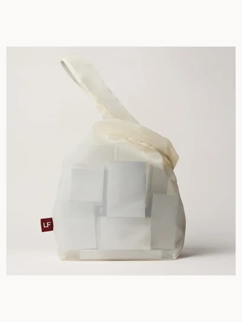 Sheer white gift bag with fabric handle and red LF logo tag, filled with wrapped advent calendar boxes