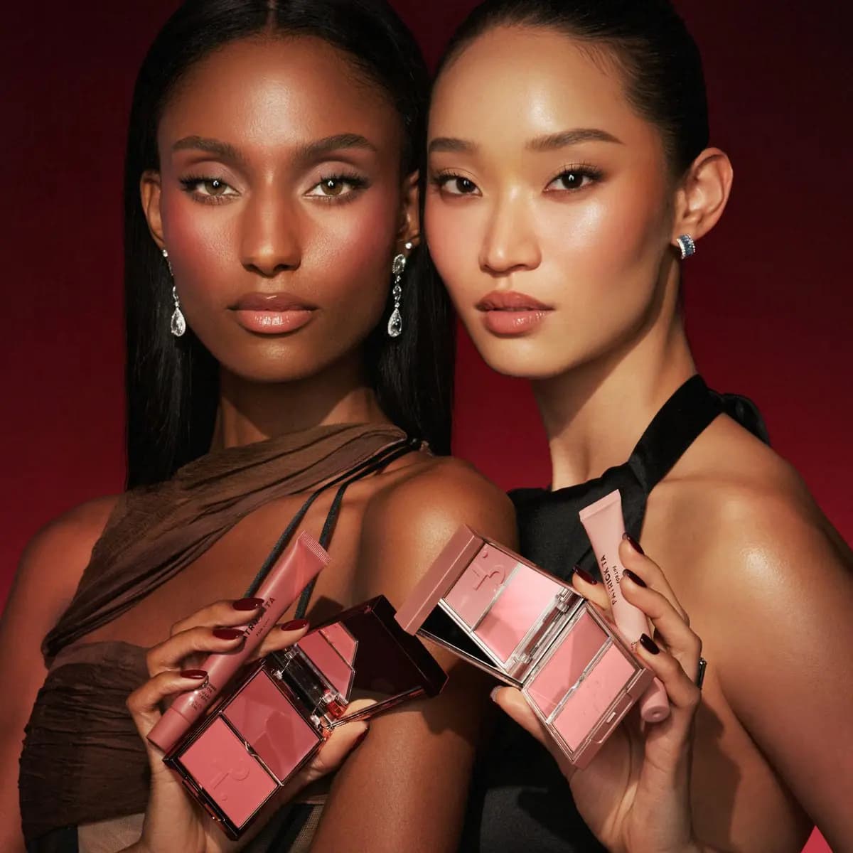 Two models holding Patrick Ta Major Headlines Blush & Balm Sets against a deep red background