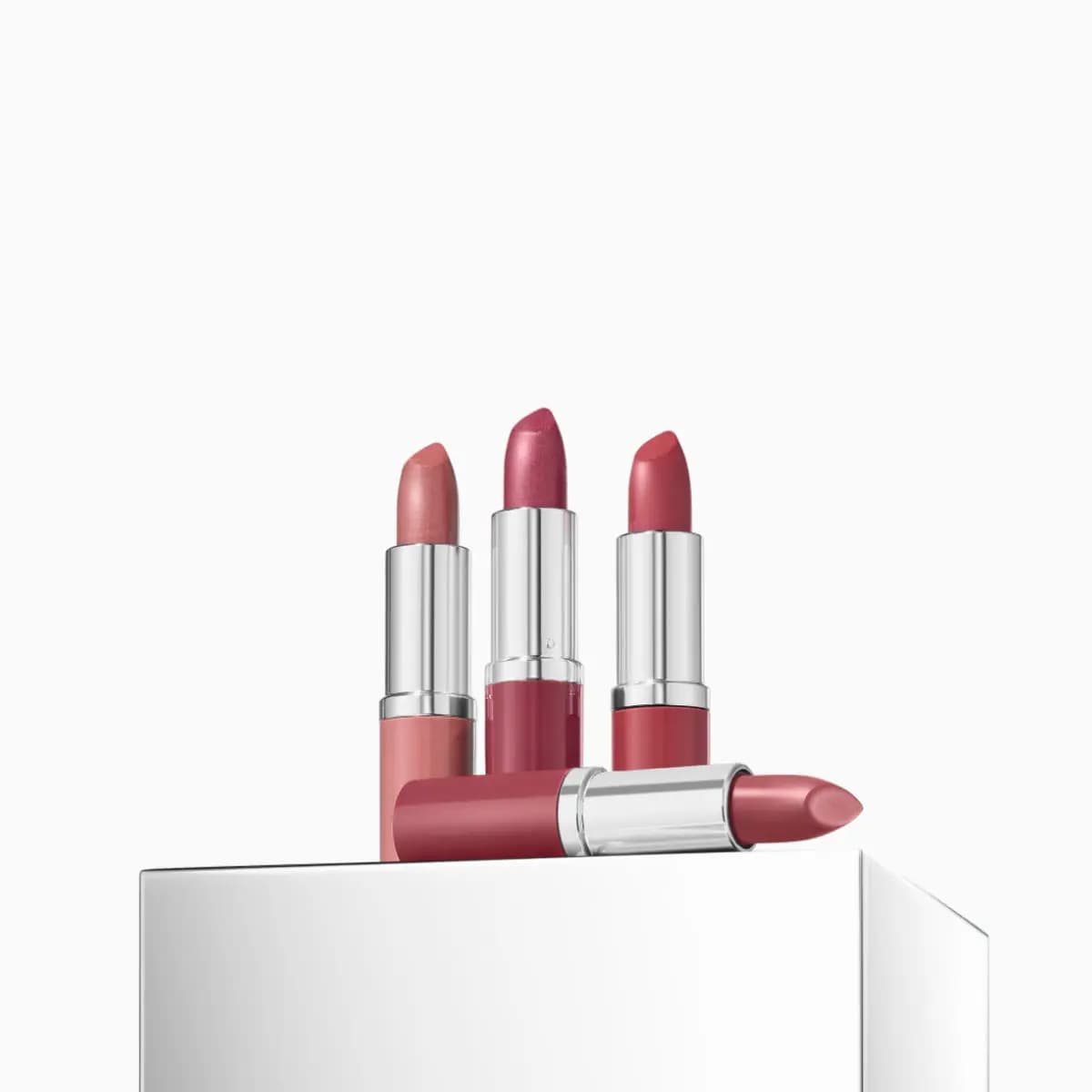Four bullet lipsticks in nude, shimmery berry, rose and mauve with silver casings on a mirrored plinth