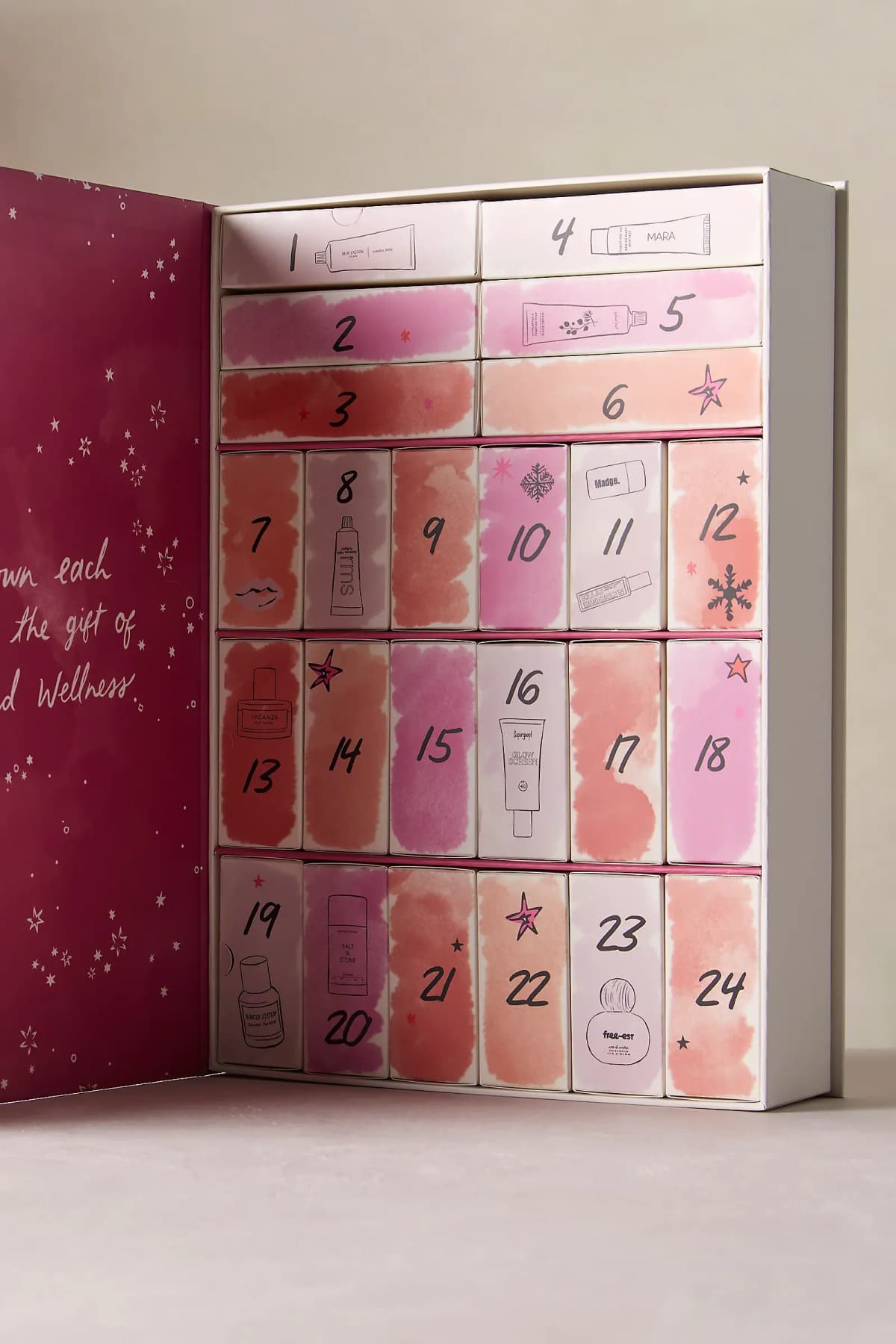 Calendar opened to reveal 24 numbered drawers with watercolour pink and coral fronts and line-drawn product sketches