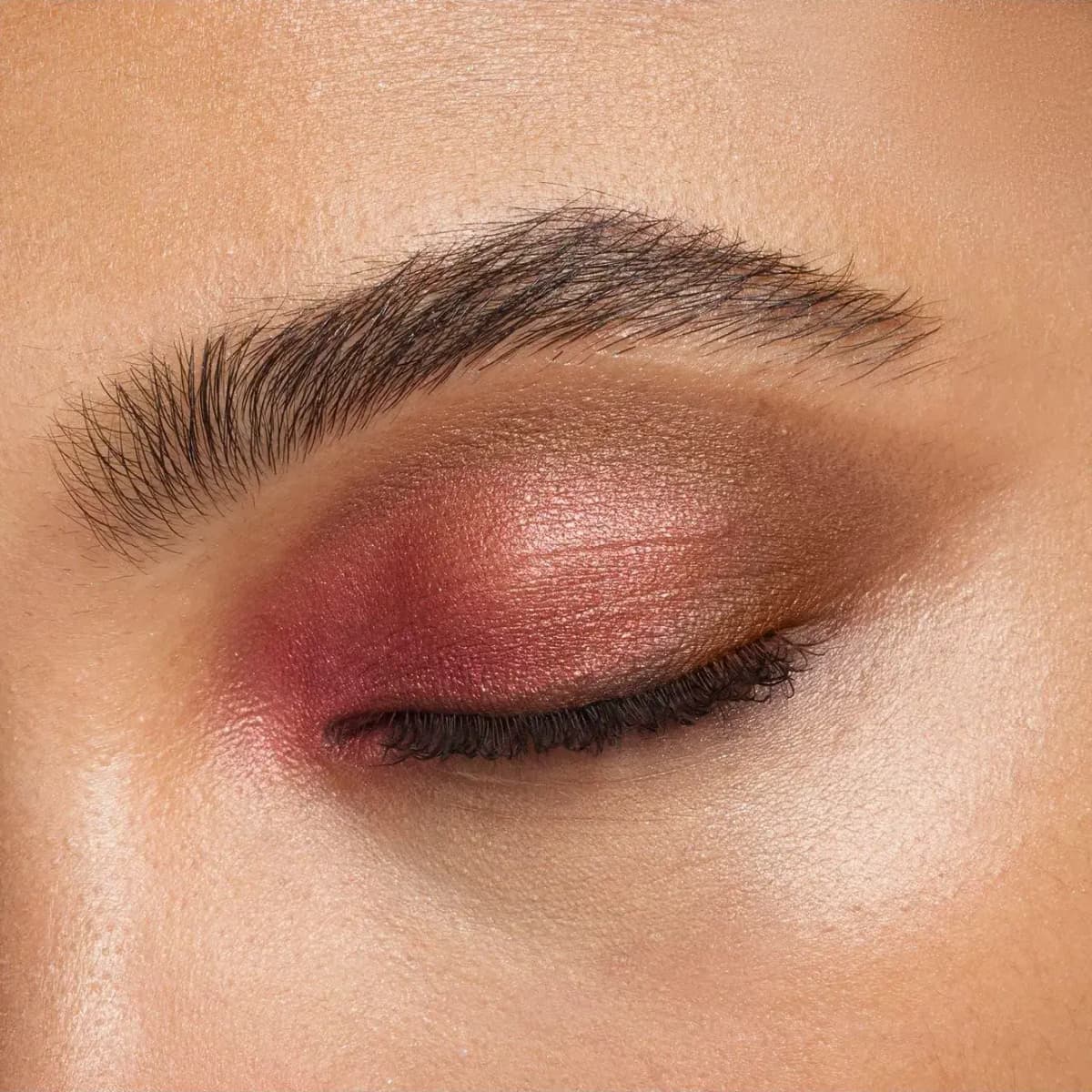 Closed eye wearing shimmering berry-pink shadow on the inner lid, a peachy centre and a bronze outer edge