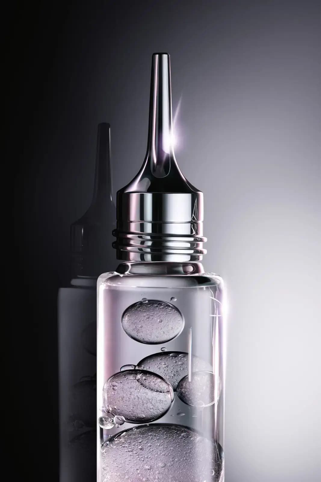 Close-up of a clear vial holding gel bubbles beneath a chrome threaded nozzle, against a dark grey gradient