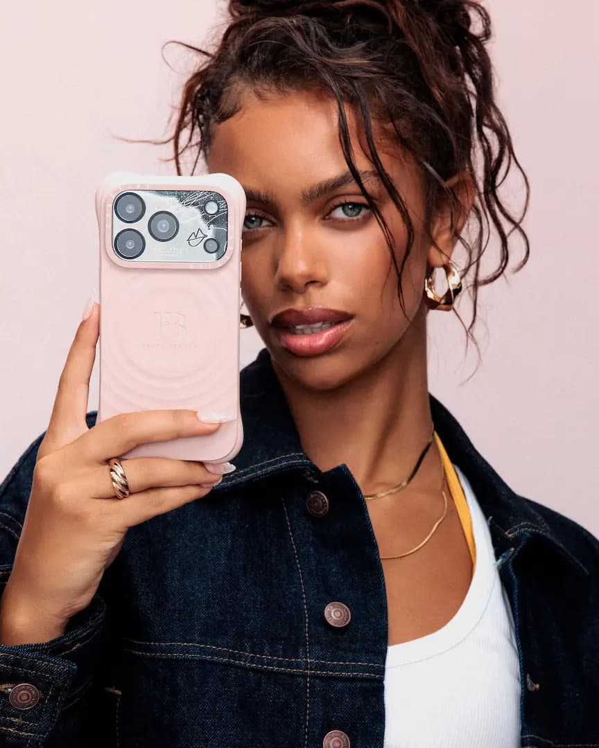 Fenty Beauty x CASETiFY mirror phone case collection: model holds a blush pink ripple-textured iPhone case over one eye
