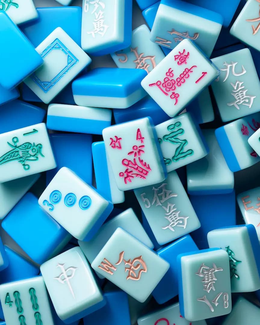 Close-up pile of glossy two-tone blue tiles with pink flower, green bamboo, blue dot and white character engravings