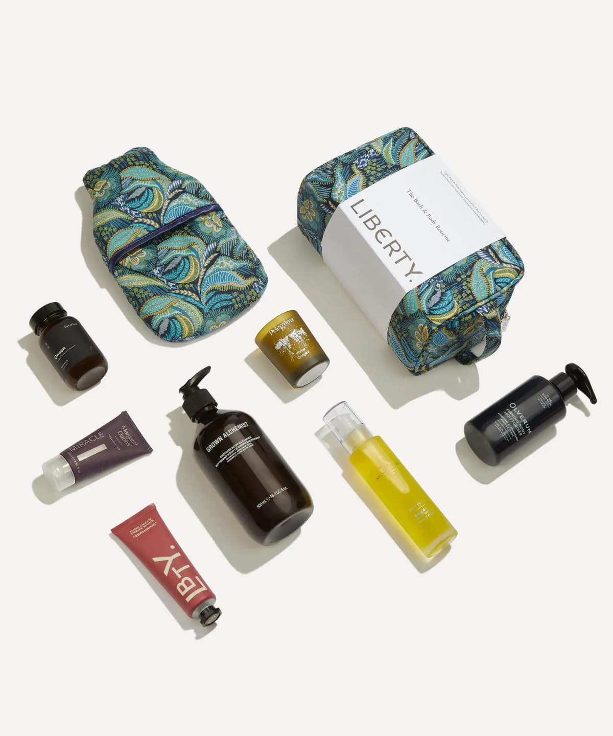 Flat lay of the kit's products beside a teal Medusa print hot water bottle and wash bag with Liberty paper band