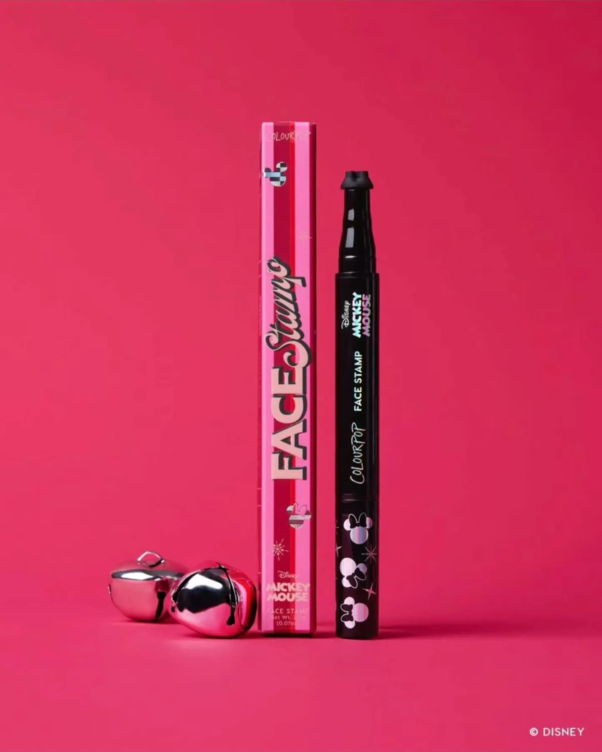 Pink striped Face Stamp box beside a black Mickey Mouse face stamp pen with Minnie bow icons, plus silver bells