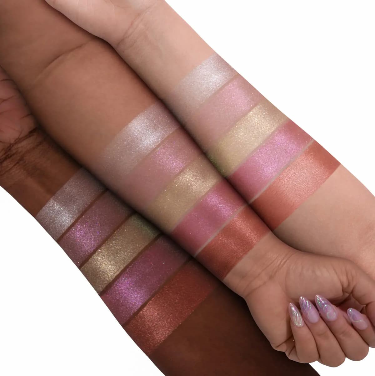 Two arms showing five glowing highlighter swatches ranging from champagne to pink to bronze across skin tones