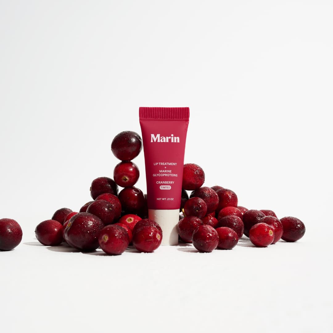 Cranberry tinted mini tube standing among a pile of fresh, glossy cranberries