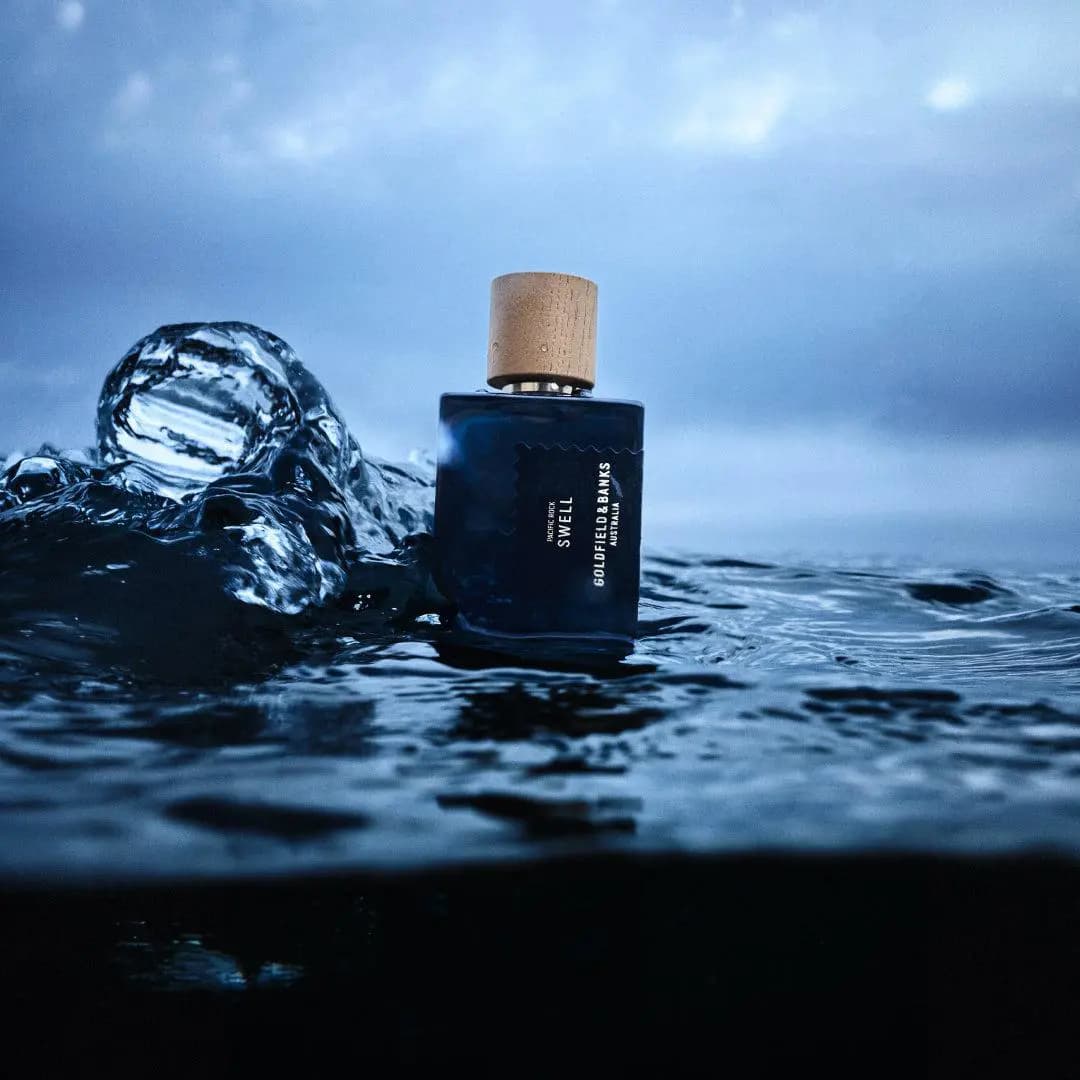 Navy Pacific Rock Swell bottle floating in dark ocean water beside a splashing wave under a cloudy sky
