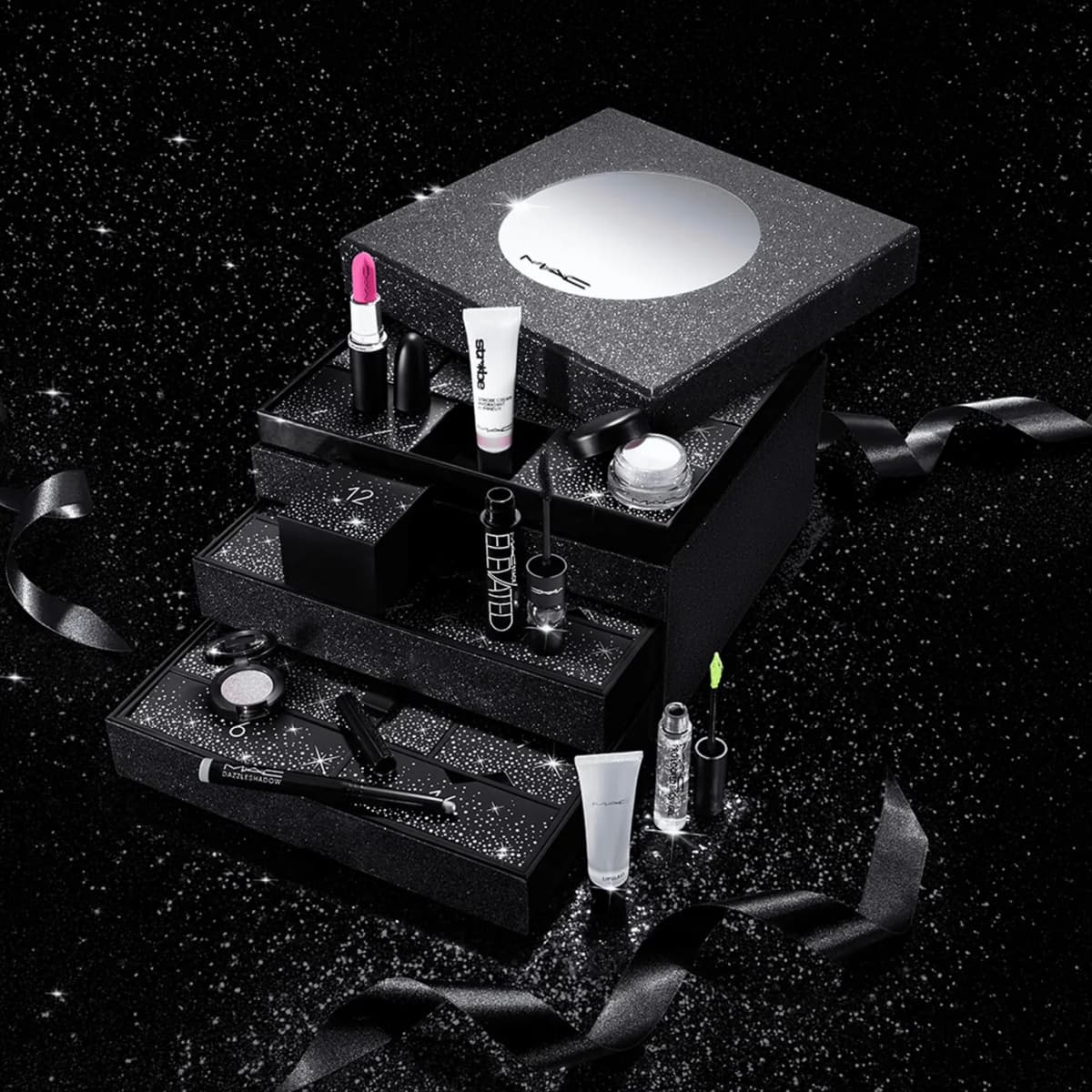 Calendar on starry black backdrop, drawers open showing pink lipstick, Strobe Cream, Elevated mascara and Lipglass