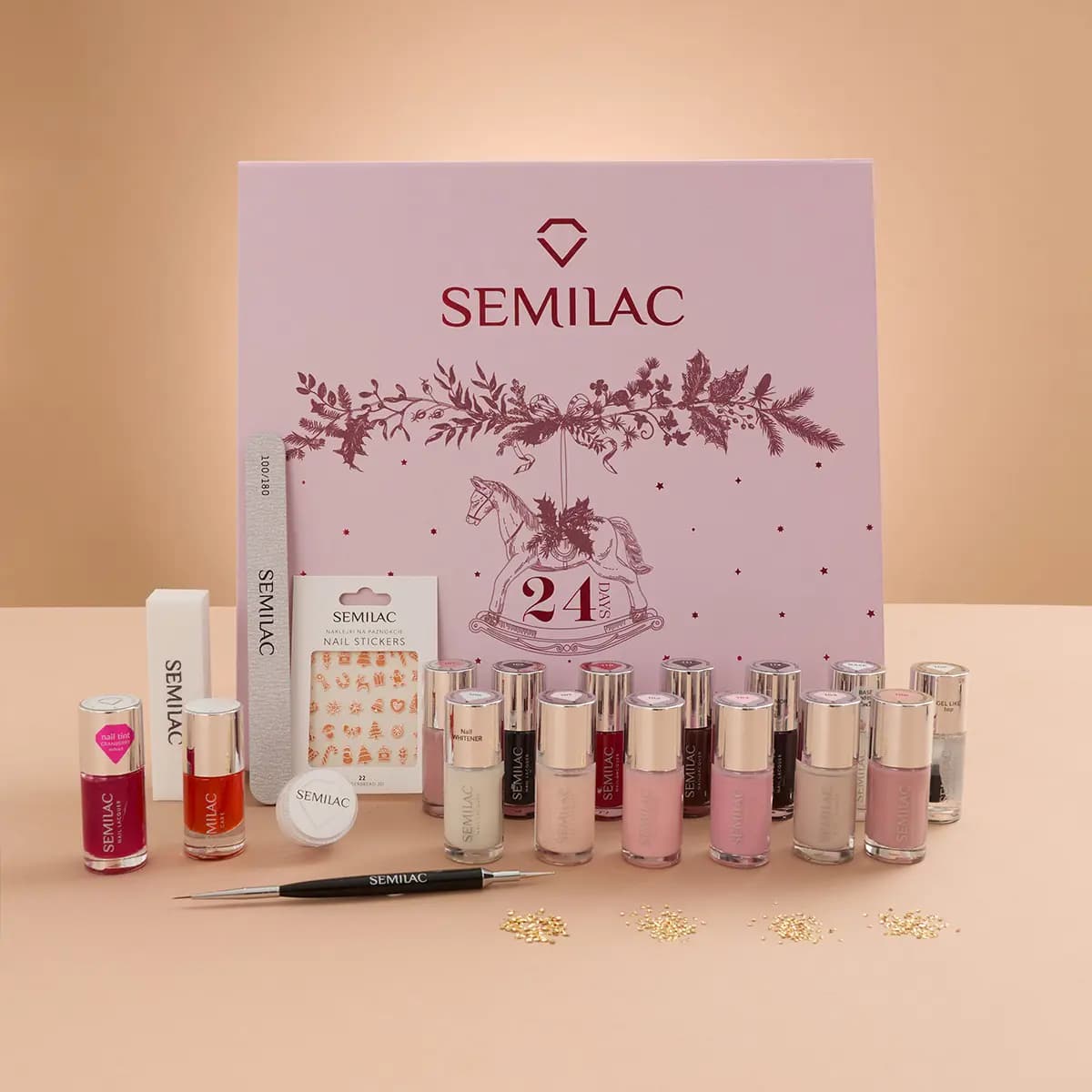 Calendar box behind nude, pink and berry polishes, nail stickers, file, buffer, dotting tool and gold studs