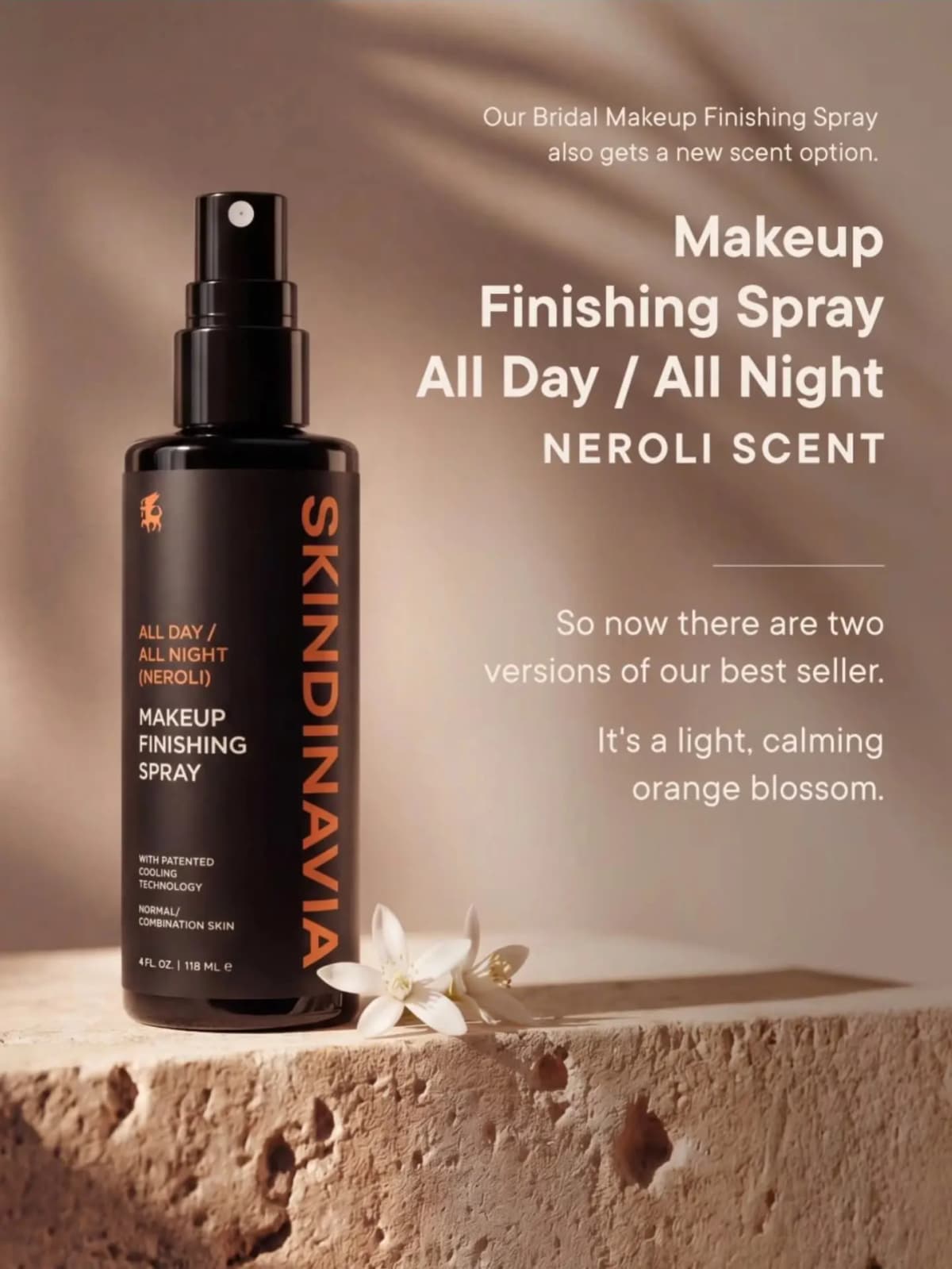 Black All Day / All Night Neroli spray with orange text on a stone ledge beside white orange blossoms