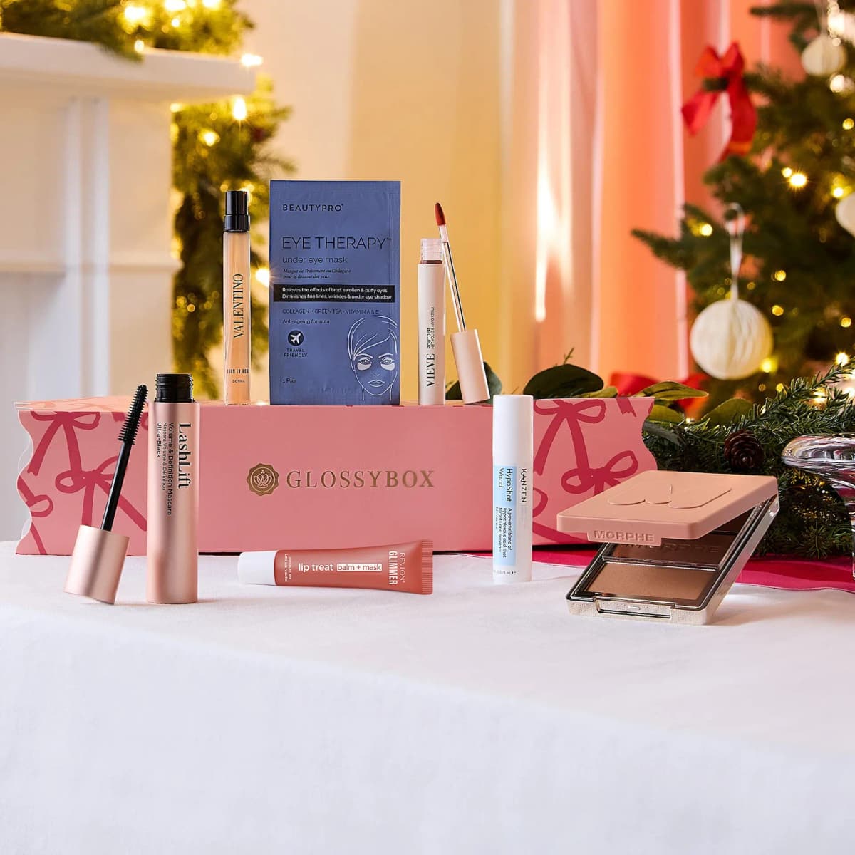 Cracker products incl. LashLift mascara, Vieve, Kanzen and Morphe palette around a pink GLOSSYBOX cracker by a tree