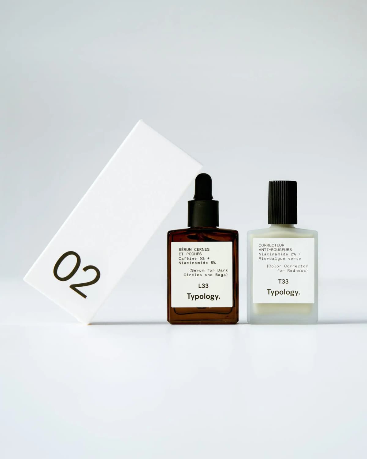White box numbered 02 leaning beside Typology L33 dark circles serum in amber glass and T33 redness color corrector.
