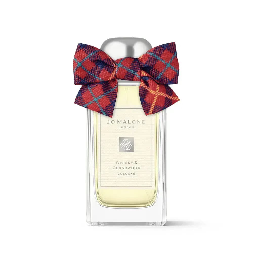 Whisky & Cedarwood Cologne bottle wearing a red, navy and teal tartan bow on a white background