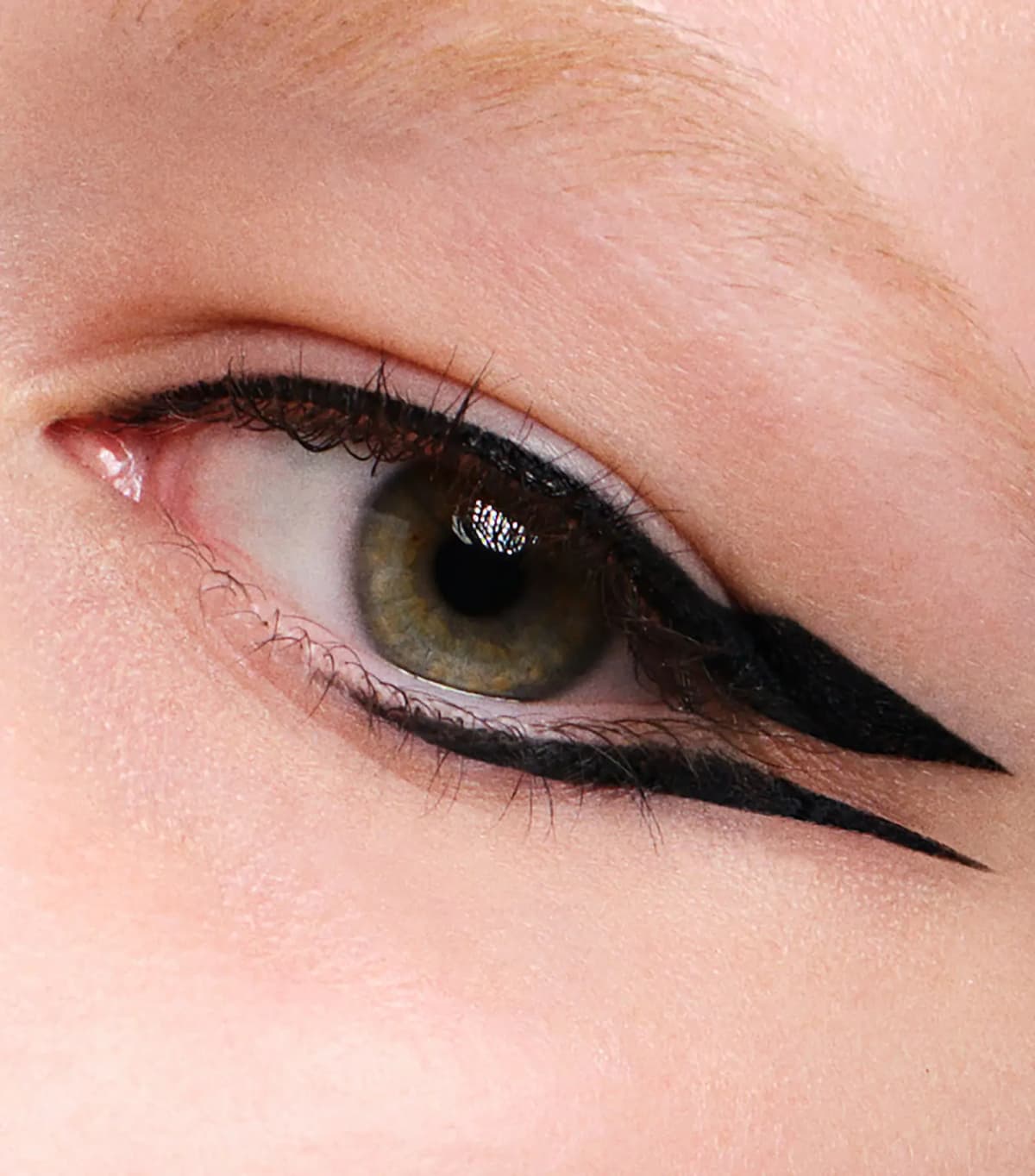 Close-up of a green eye with a bold black graphic double-winged eyeliner look