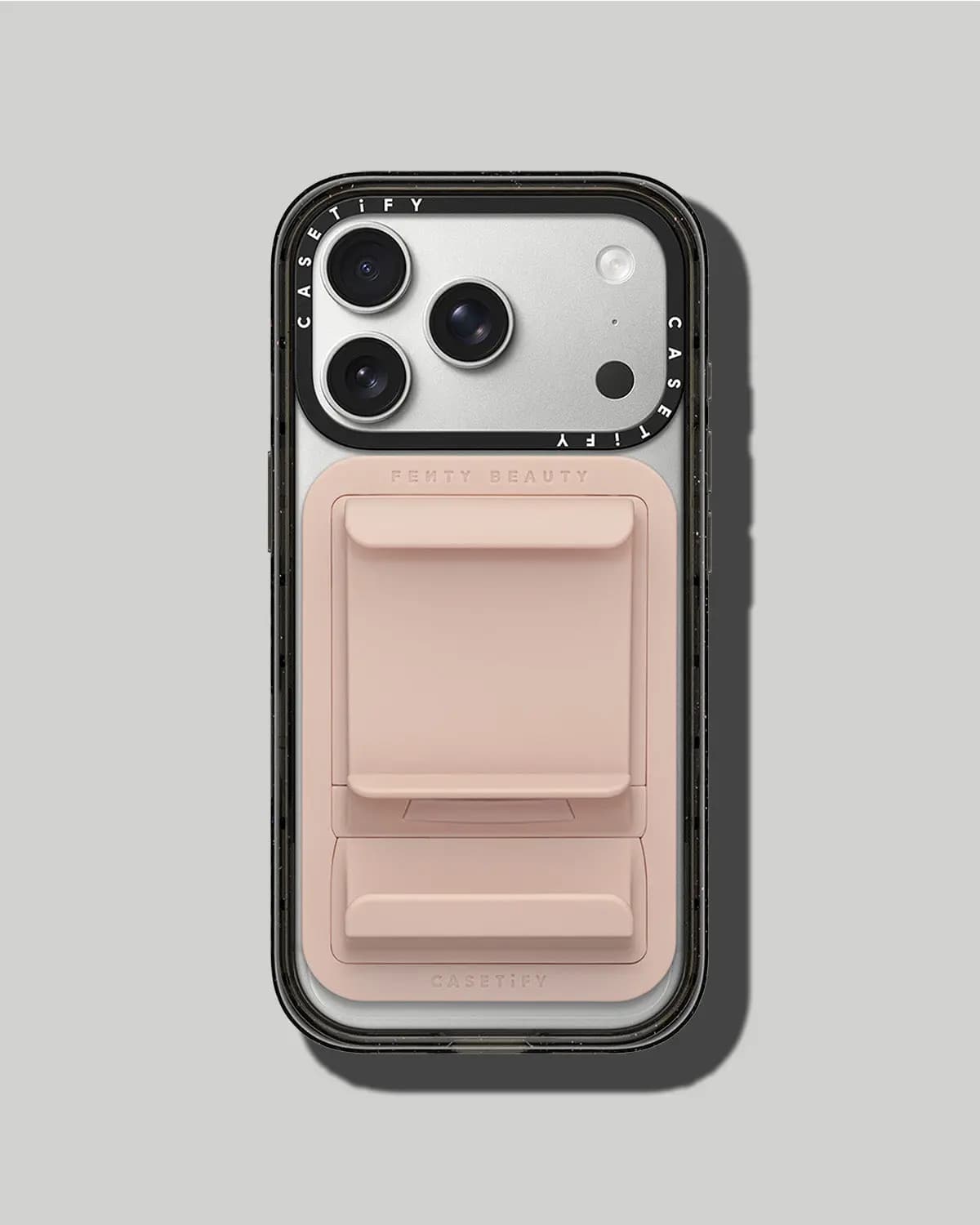 Black clear iPhone case with a blush pink MagSafe lip gloss holder marked Fenty Beauty and CASETiFY