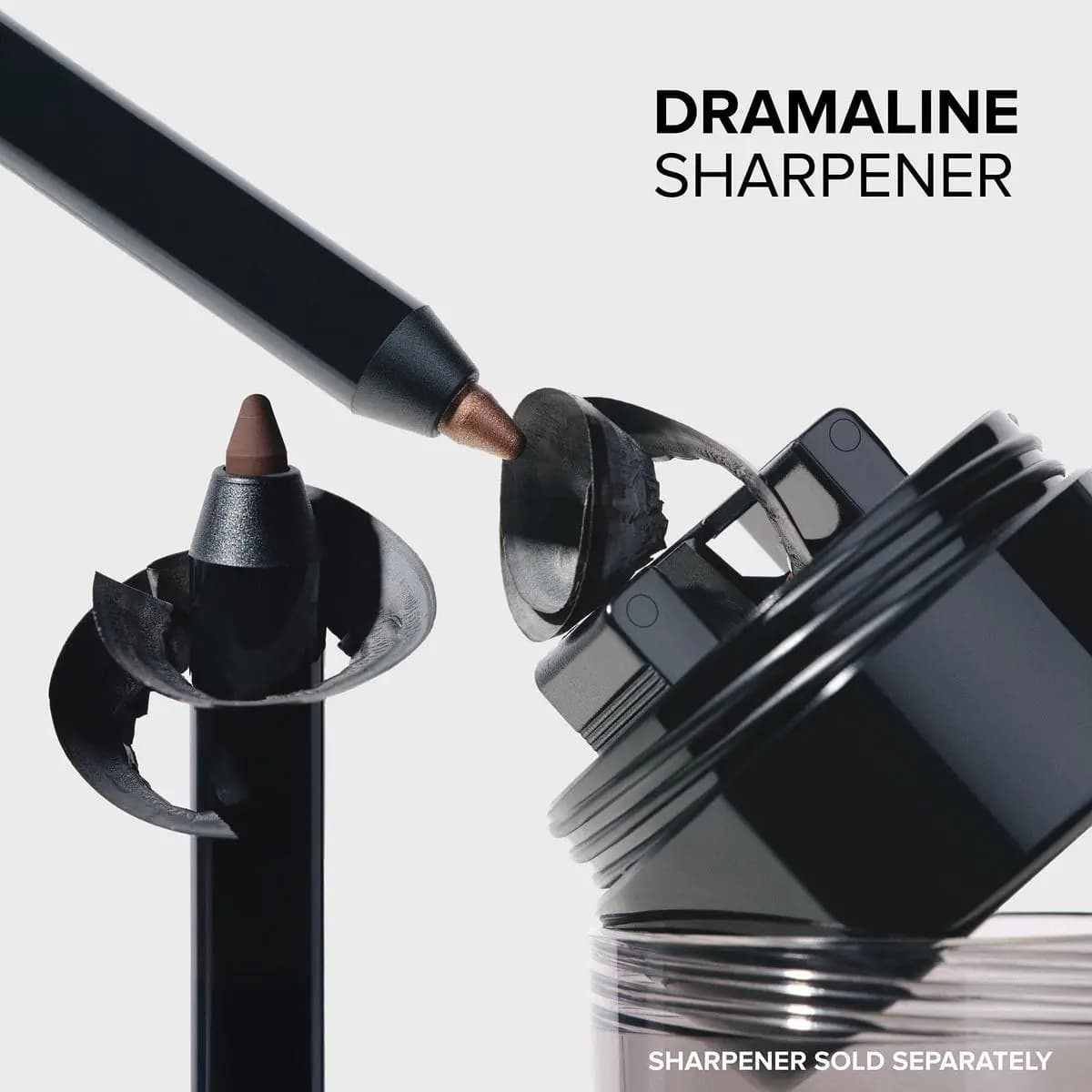 Black eyeliner pencil being sharpened over a jar sharpener with dark shavings, labeled Dramaline Sharpener